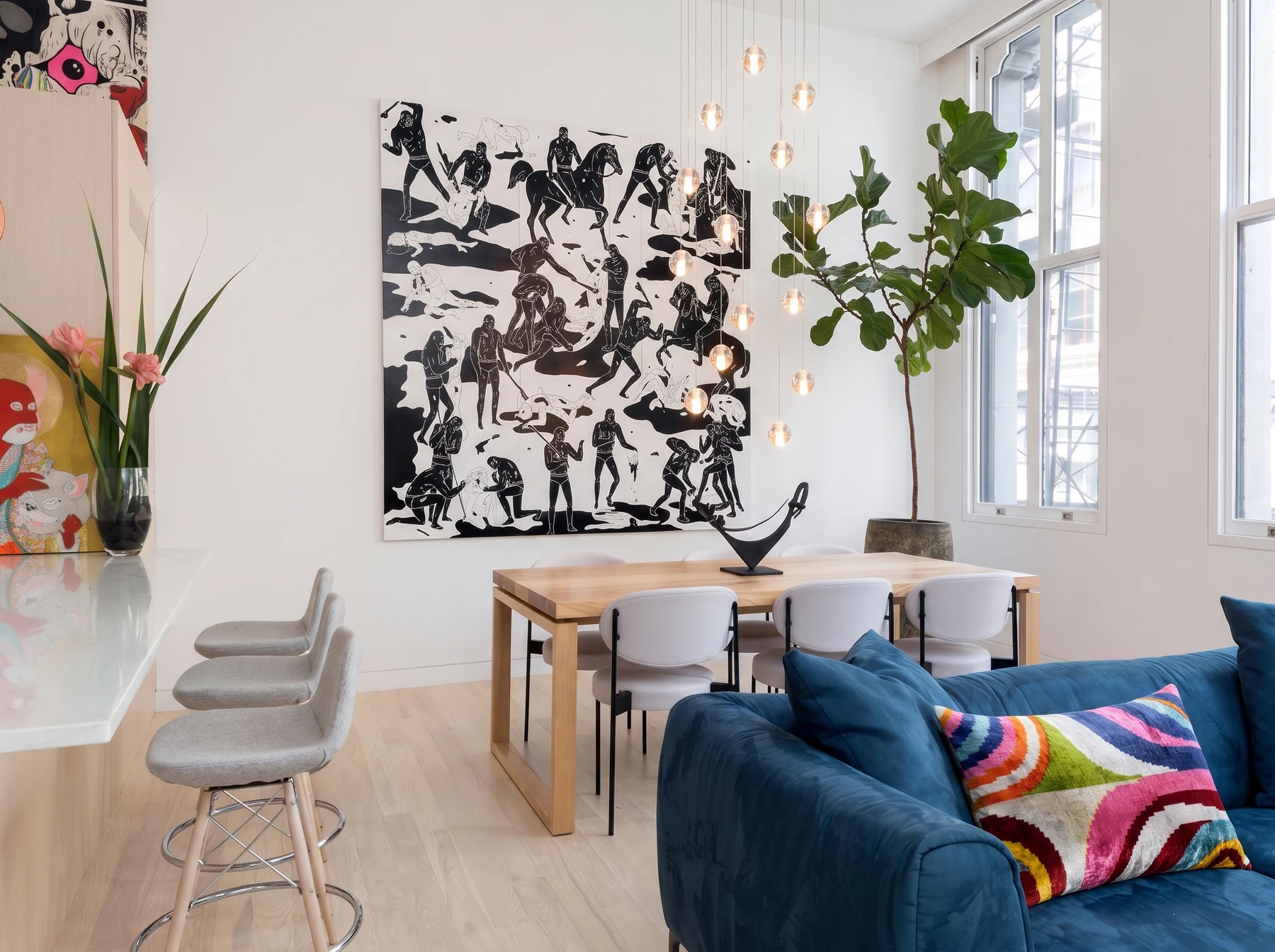 Cohen residence in Tribeca, with a blue sofa, pale timber dining table, and large monochrome artwork.