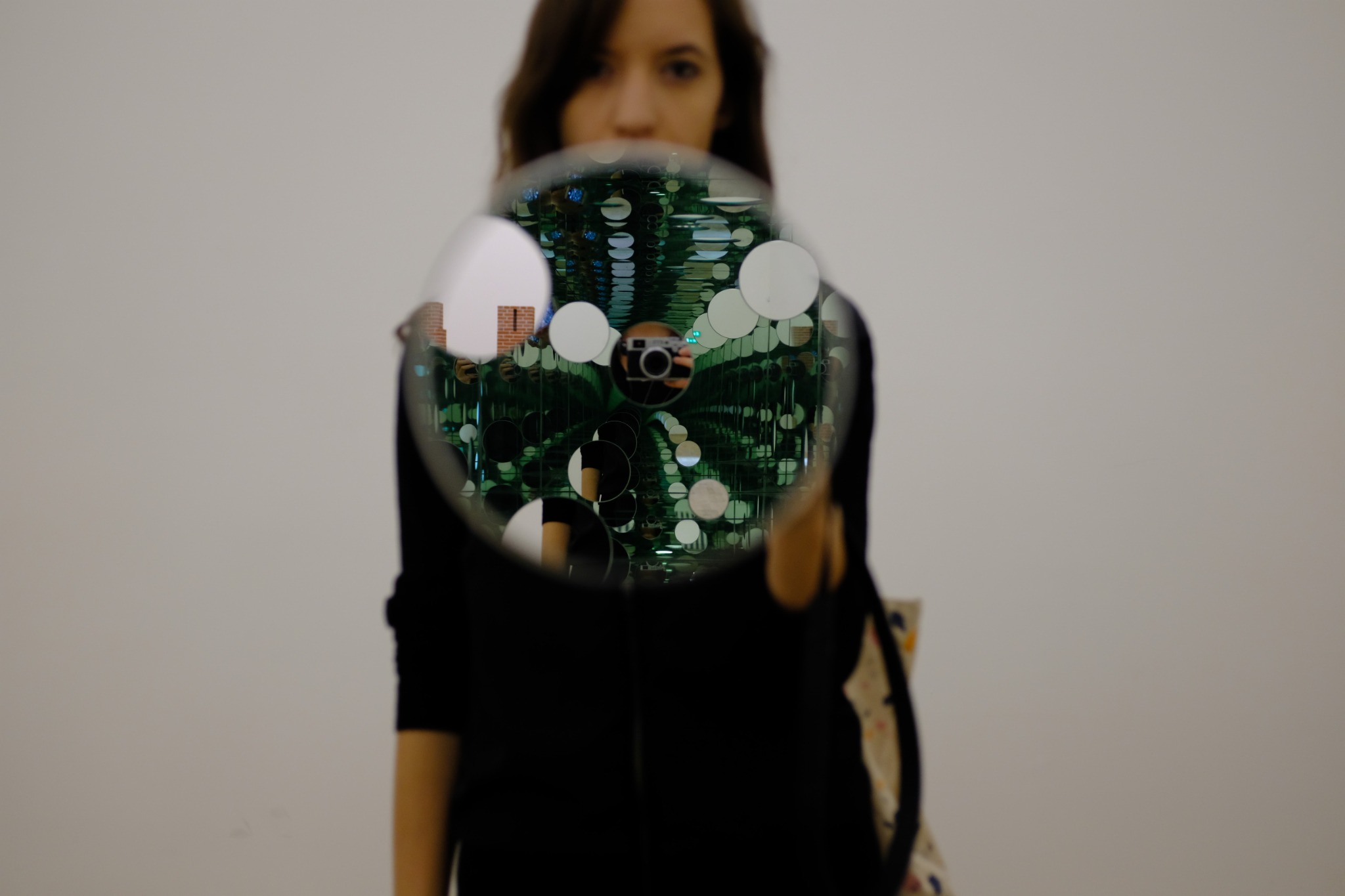 Joyce holding her camera, seen through a circular mirror and repeated reflections in London.